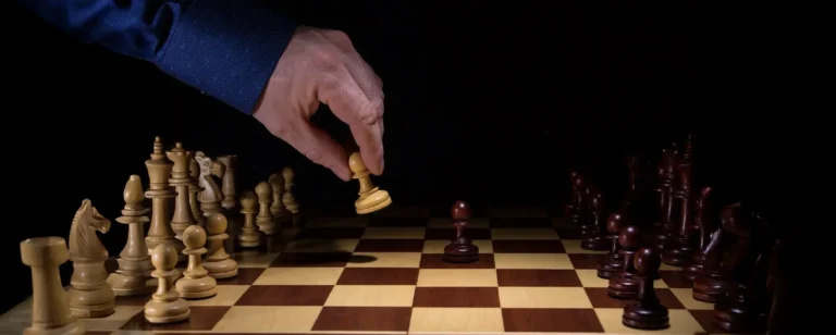 Hand holding a pawn on a chessboard