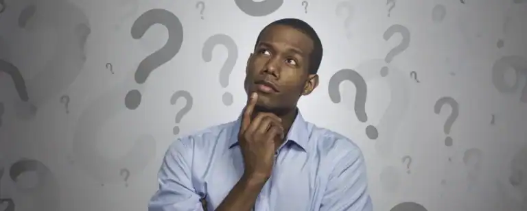 African American man with his index finger on his chin and surrounded by question marks