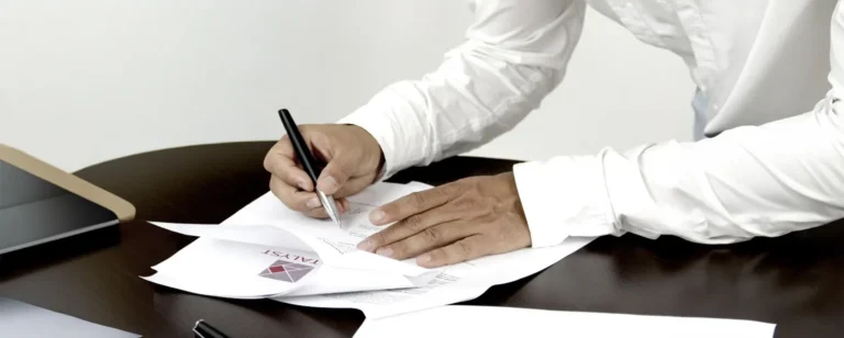 A person wearing a long sleeve shirt signing a document