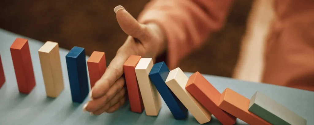 A hand stopping falling dominoes