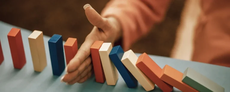A hand stopping falling dominoes