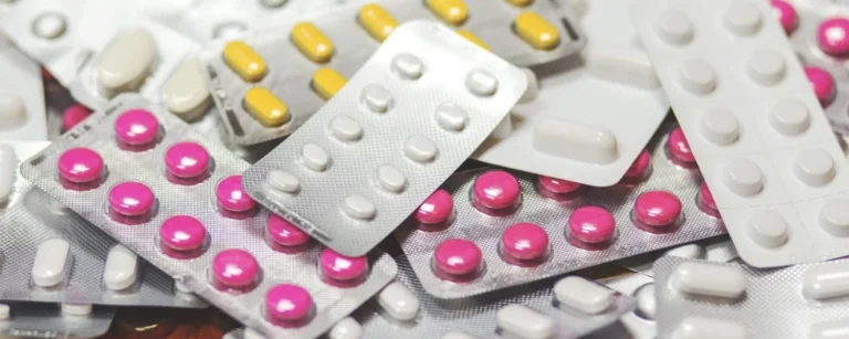 A pile of yellow, white, and pink pills in blister packs